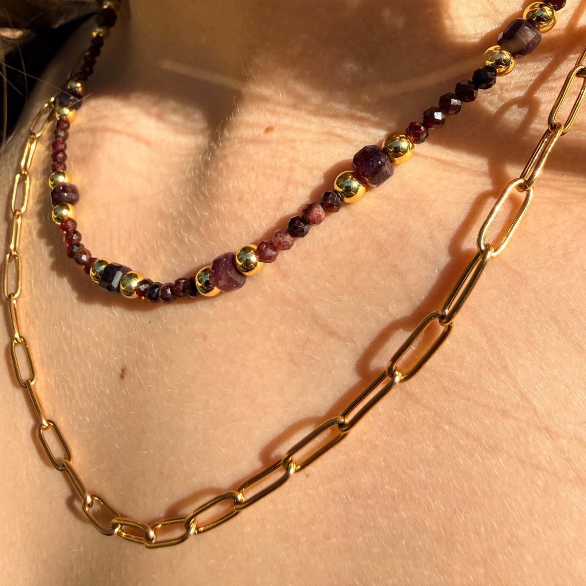 Necklace with gold chain and multicolored beads on a person's neck