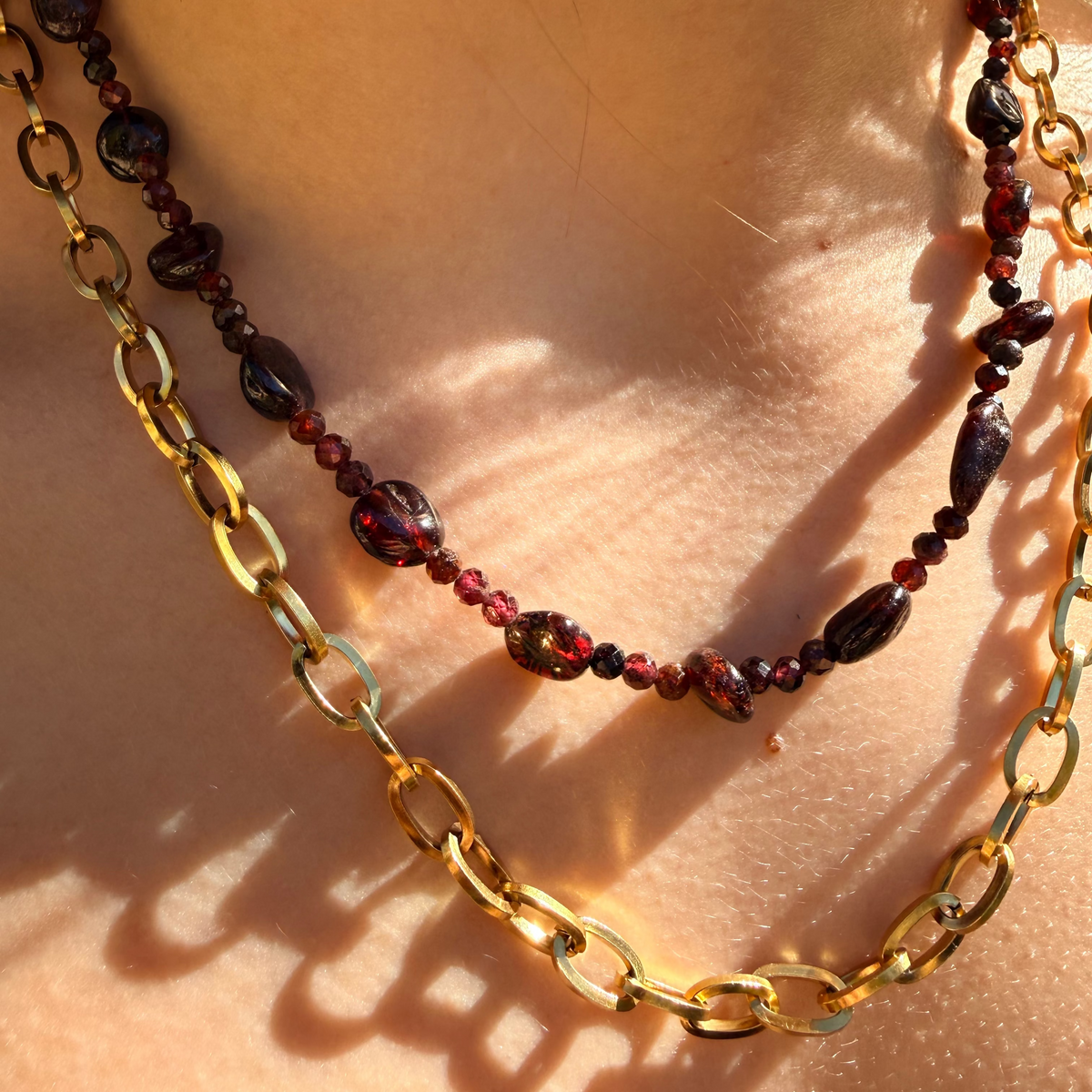 Necklace with red beads and gold chain on a person's neck