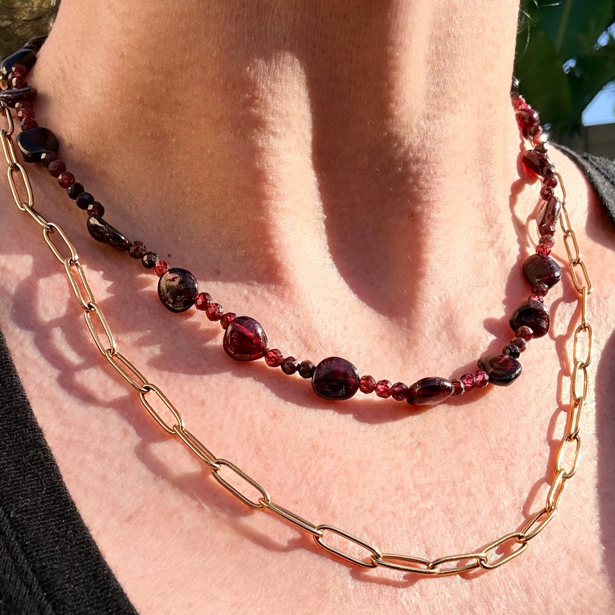 Necklace with red beads and gold chain on a person's neck