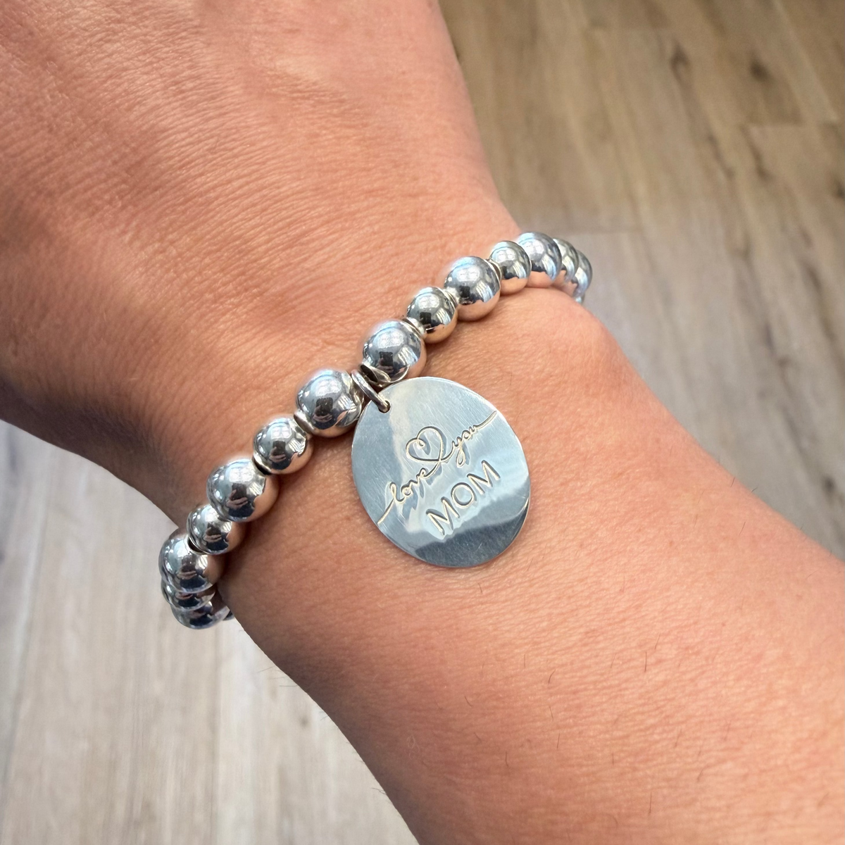 Sterling silver beaded bracelet with Love You Mom charm on woman's wrist