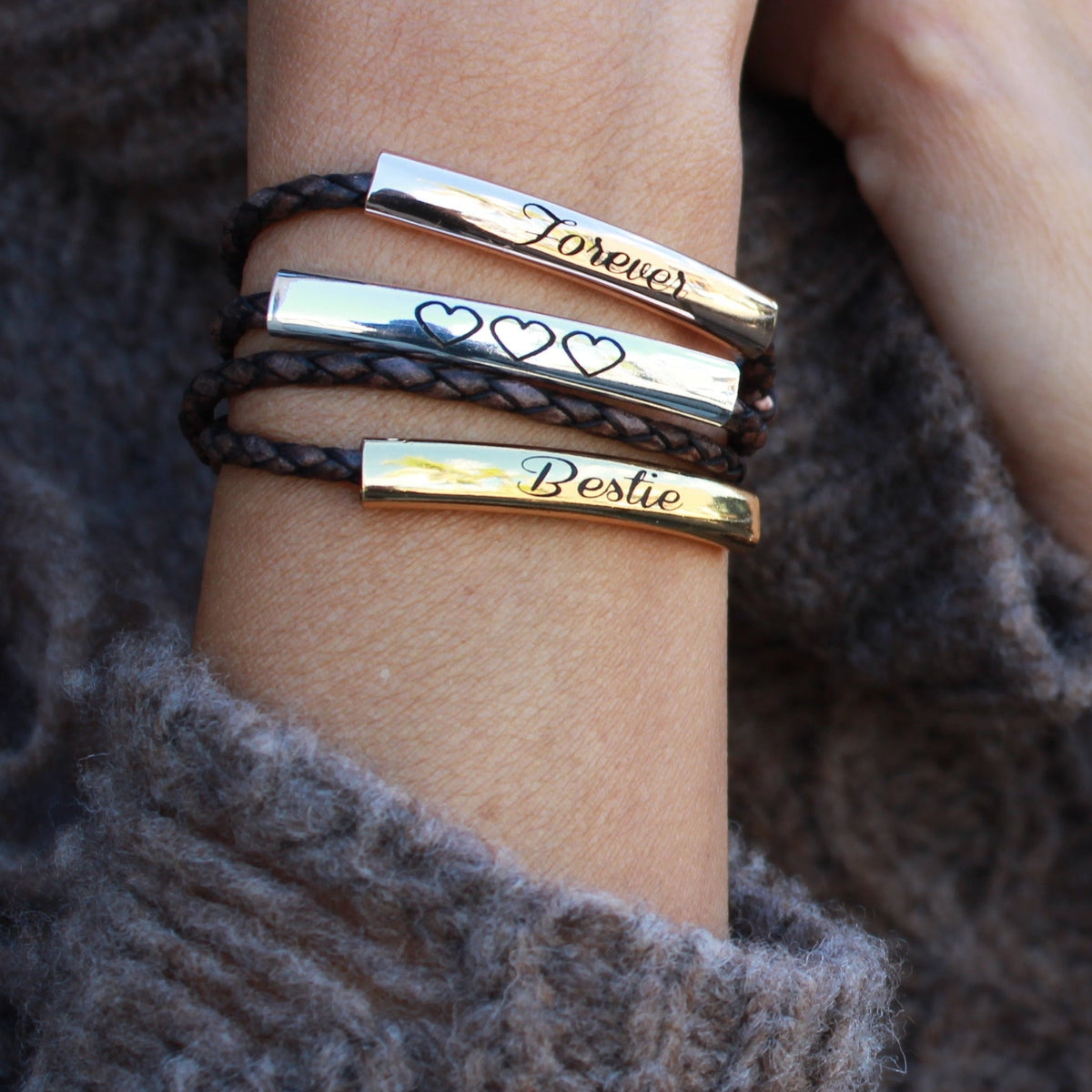Close-up of a person's wrist wearing multiple bracelets with text on a textured surface.