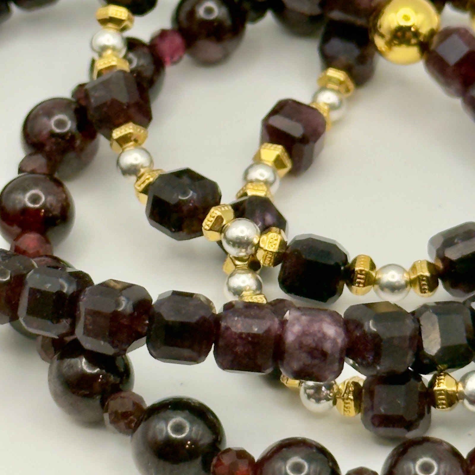 Close-up of a beaded necklace with dark beads and gold accents on a white background