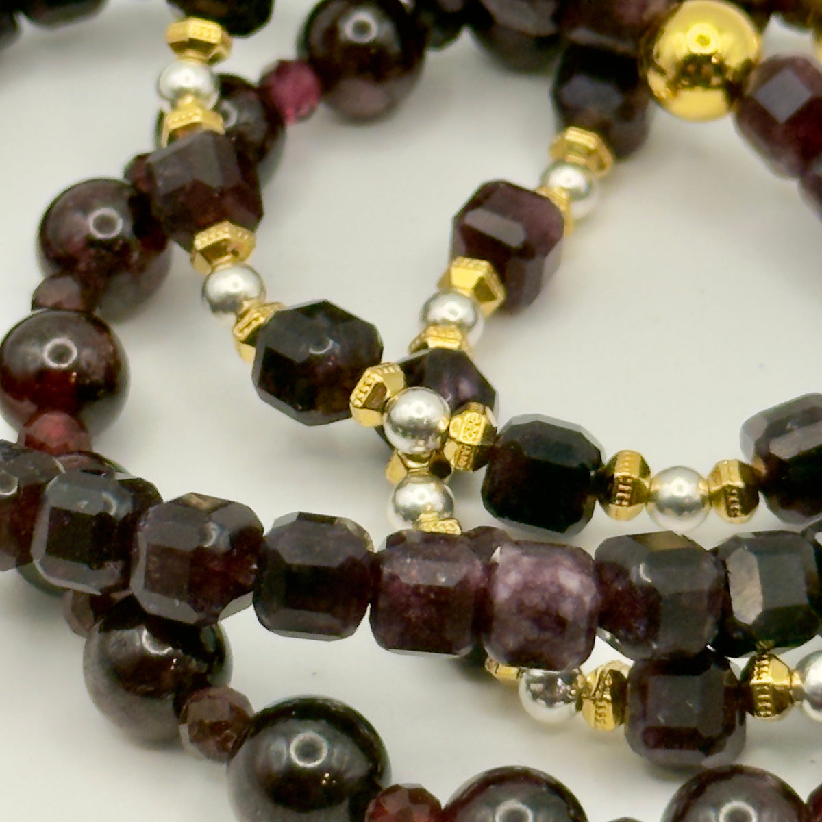 Close-up of a beaded necklace with dark beads and gold accents on a white background