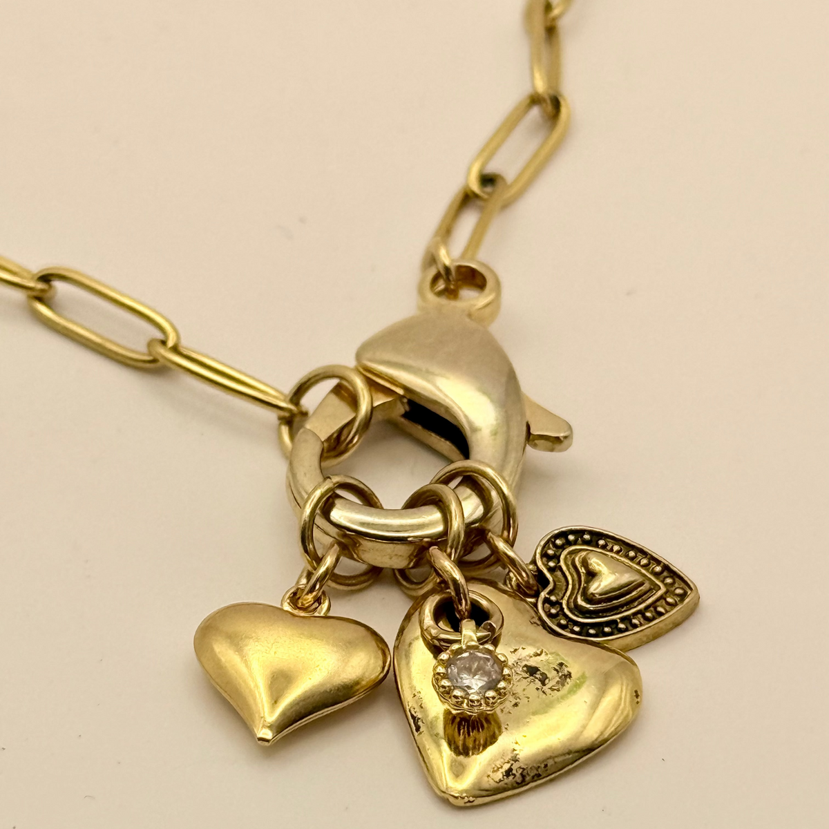 Gold necklace with heart-shaped pendants on a beige background