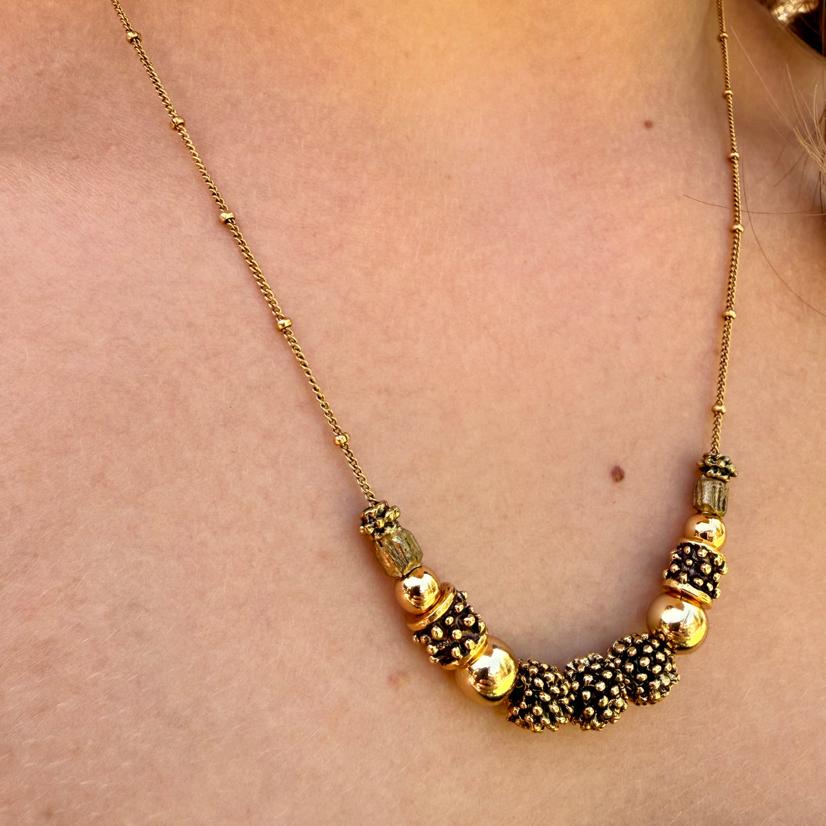 Necklace with gold and black beads on a person's neck