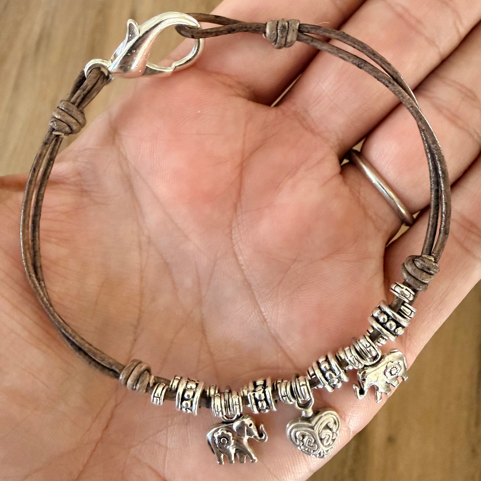 Natural brown leather anklet for women with silver-plated elephant charms, heart charm, and assorted silver beads.