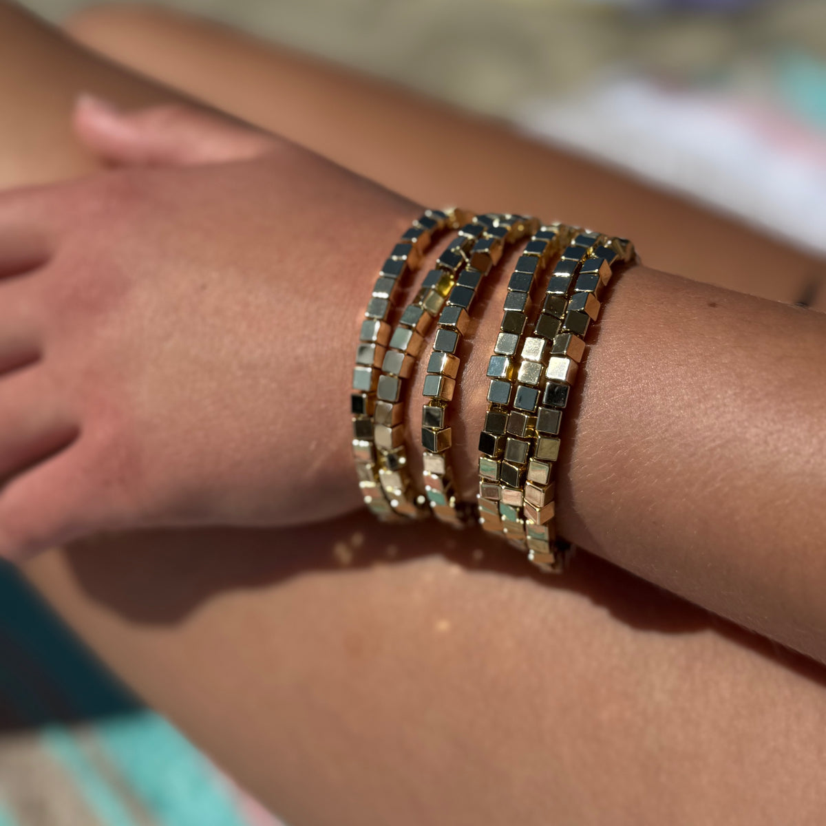 Close-up of a wrist wearing multiple metallic bracelets on a blurred background