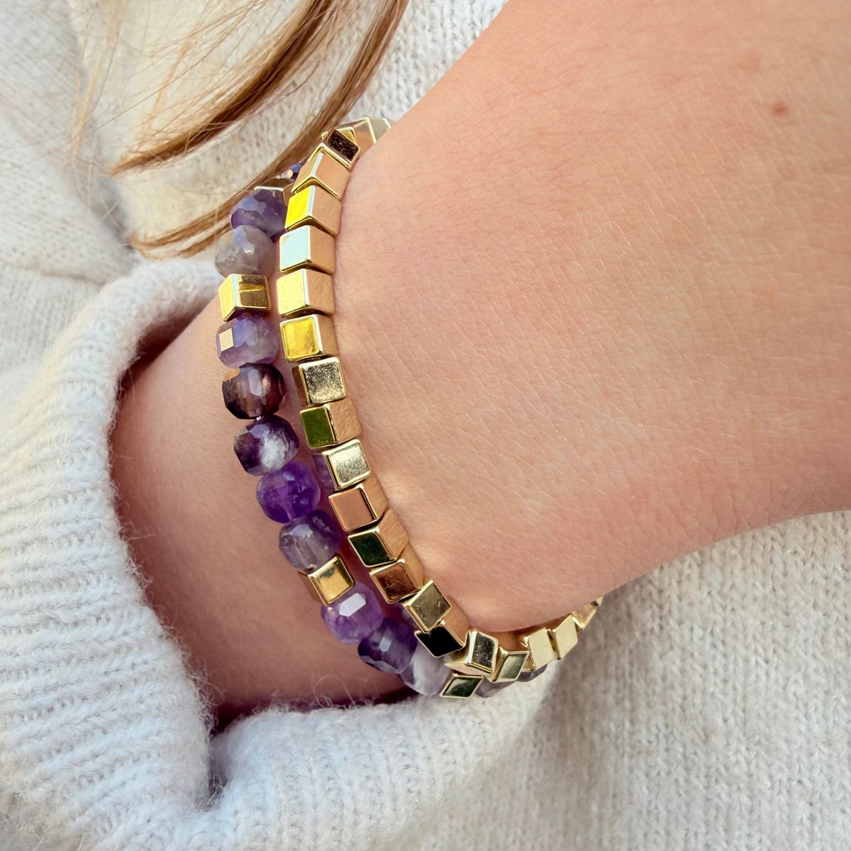 Close-up of a wrist wearing a beaded bracelet with gold accents on a light background