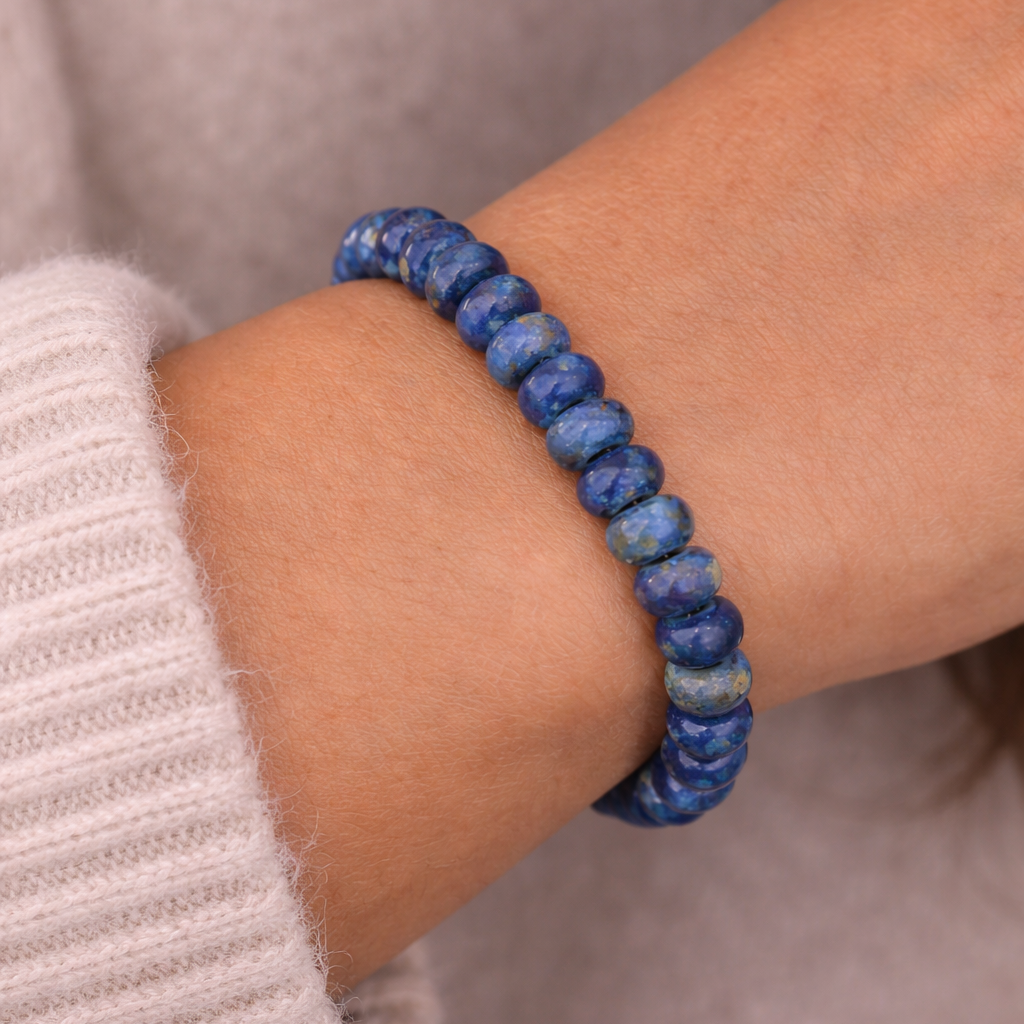 Blue beaded bracelet on a wrist with a neutral background