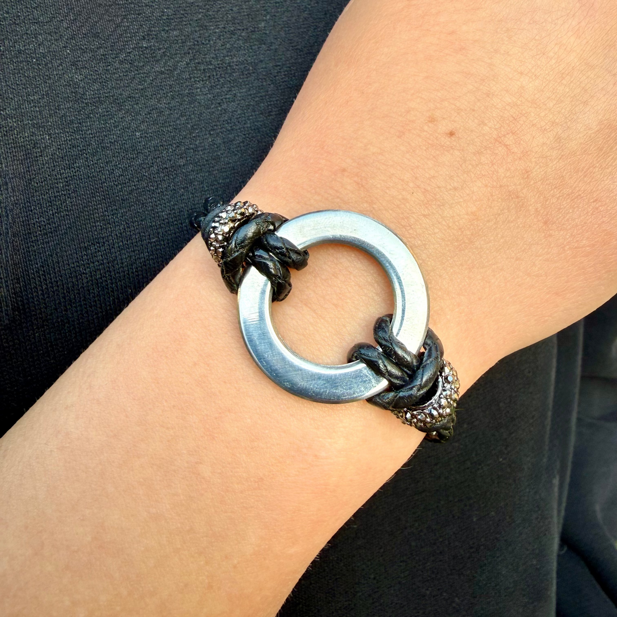 Bracelet with a circular design on a wrist against a dark background