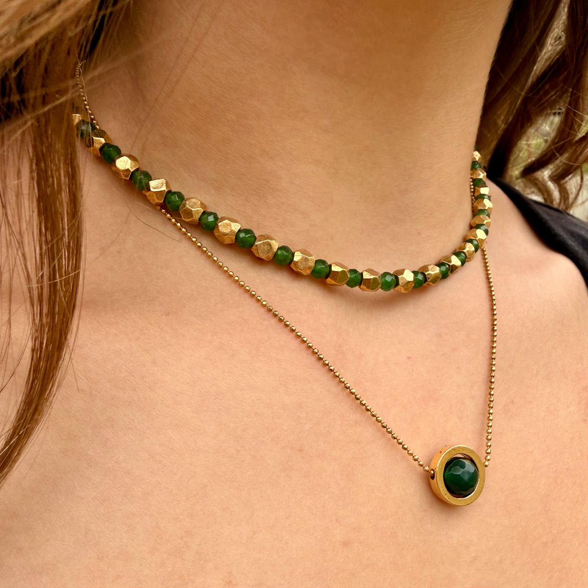 Gold and green beaded necklace on a person's neck