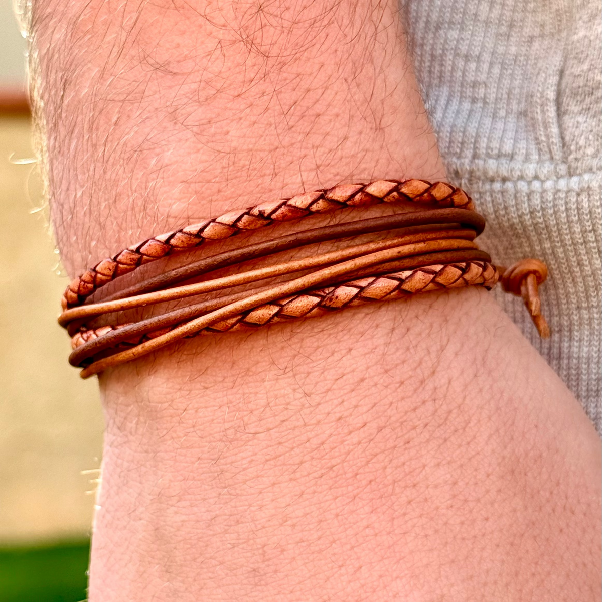 Close-up of a person's wrist wearing a braided brown leather bracelet.