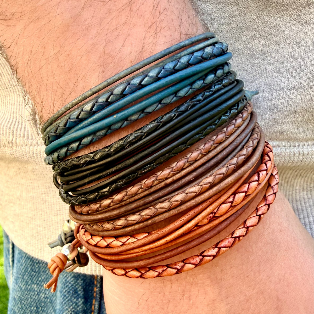 Multiple braided leather bracelets on a person's wrist with a blurred background