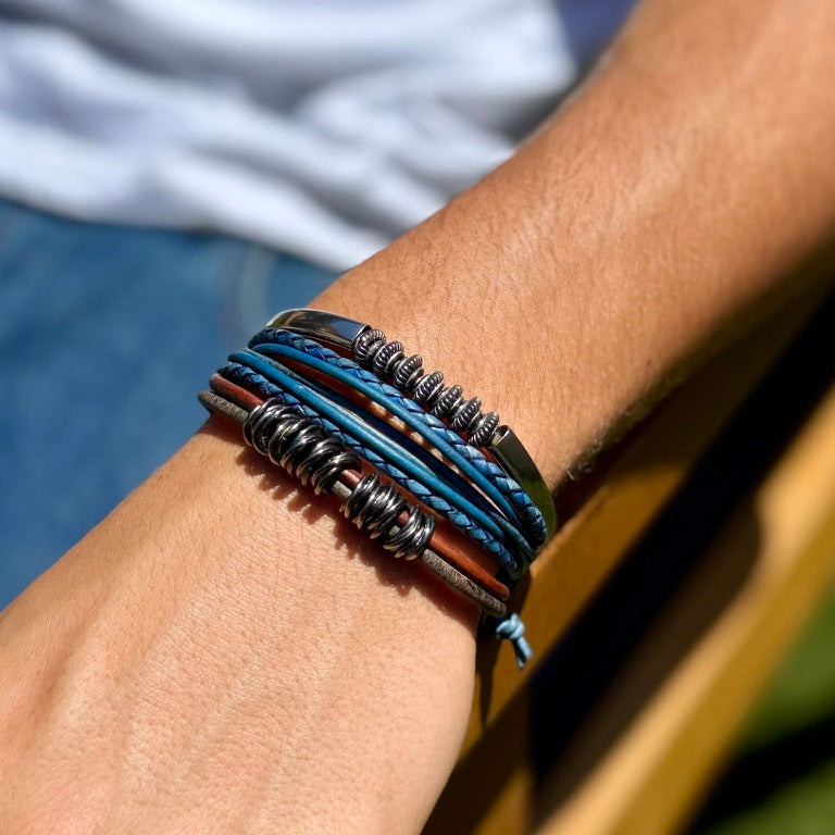 Close-up of a wrist wearing multiple layered bracelets with a blurred background