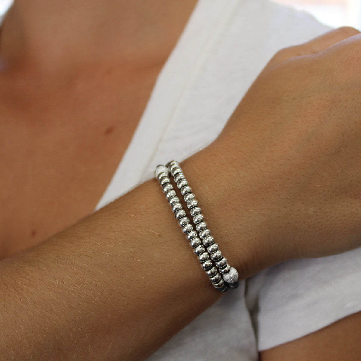 Silver beaded bracelet on a wrist with a blurred background