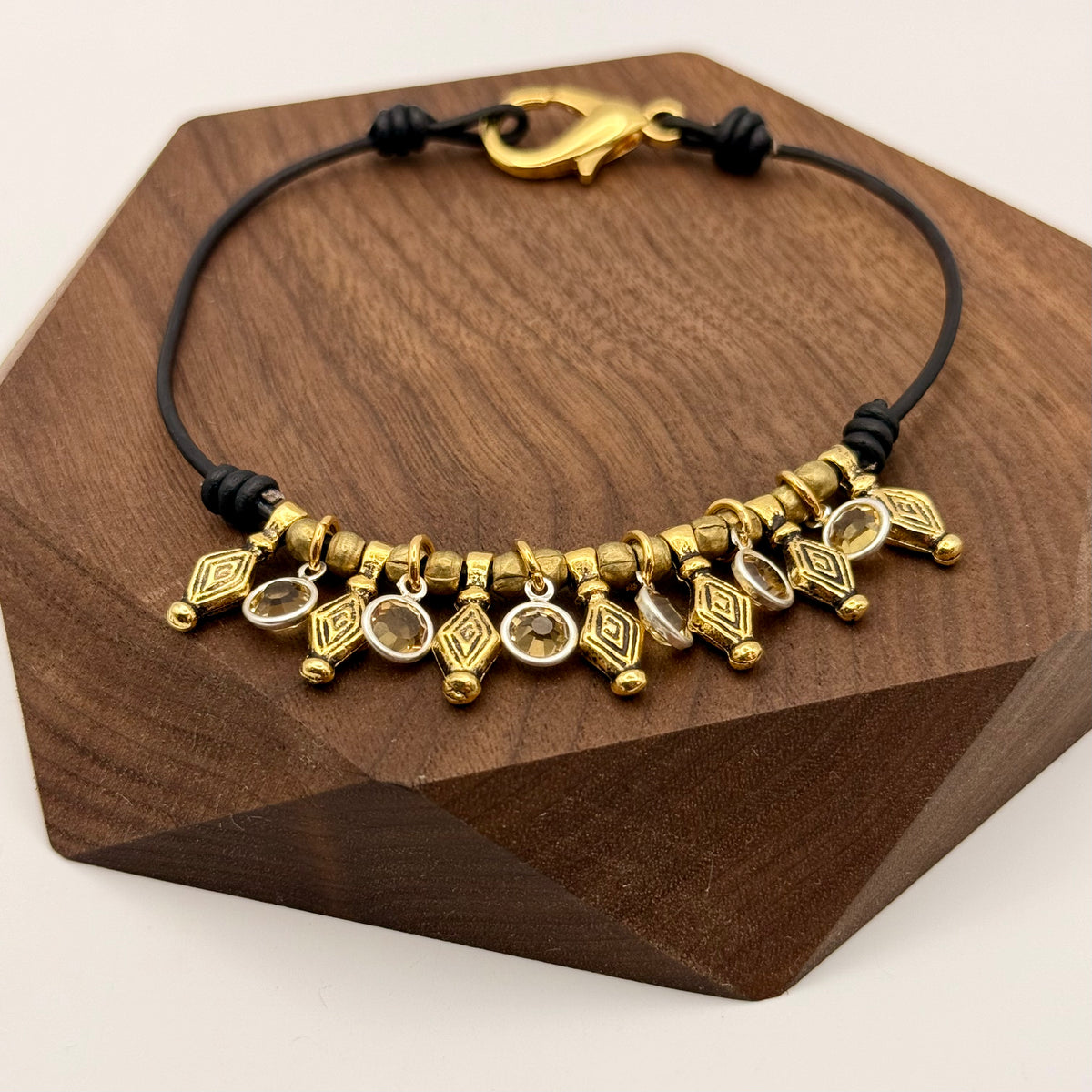 Gold and black beaded bracelet on a wooden stand