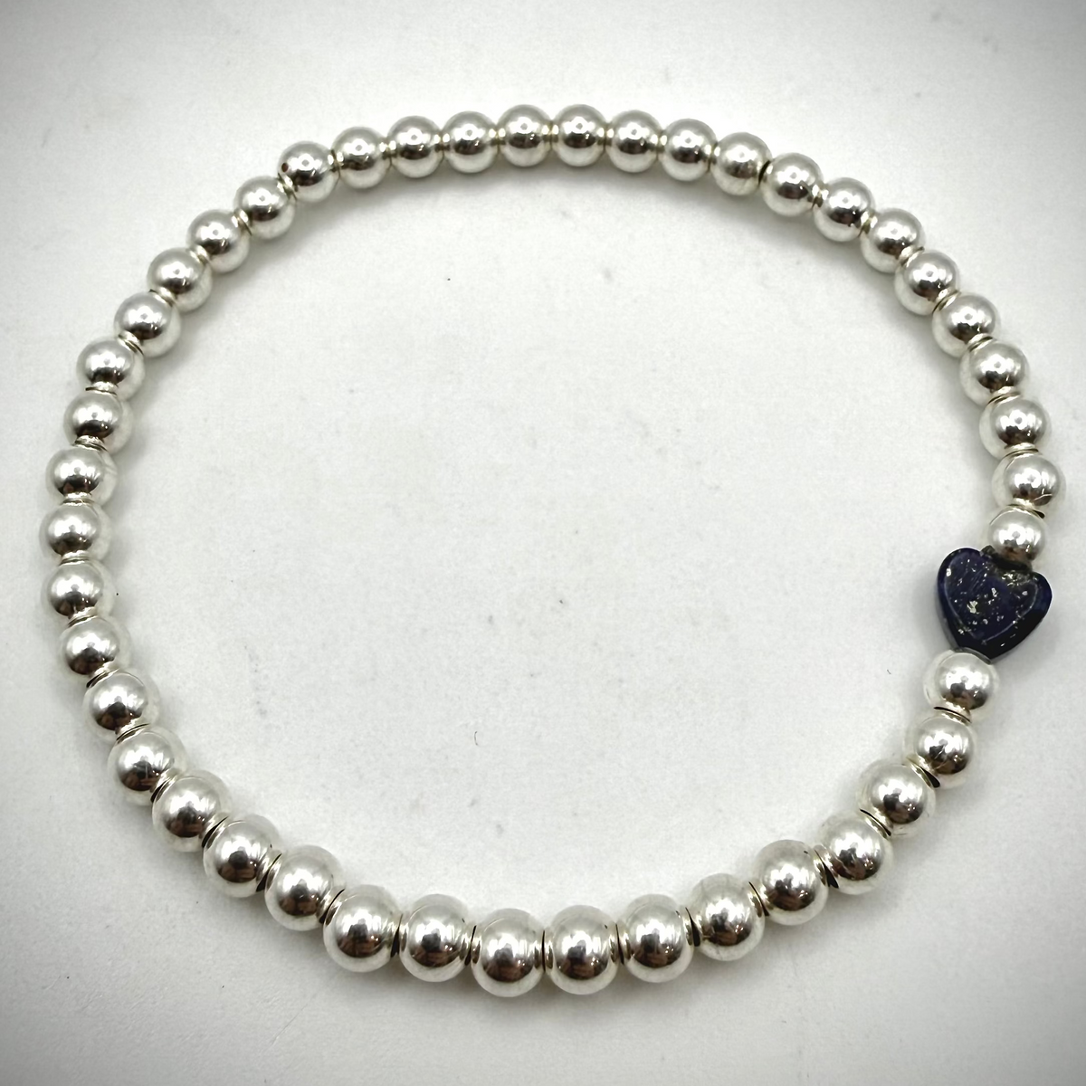 Dainty waterproof sterling silver bead stretch bracelet for women featuring a small navy blue Lapis Lazuli heart charm.