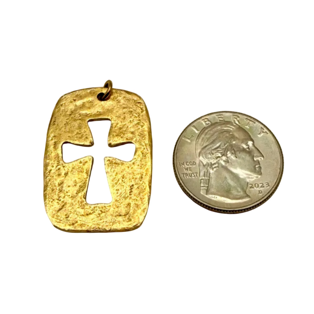 Gold pendant with cross design next to a U.S. quarter on a light gray background