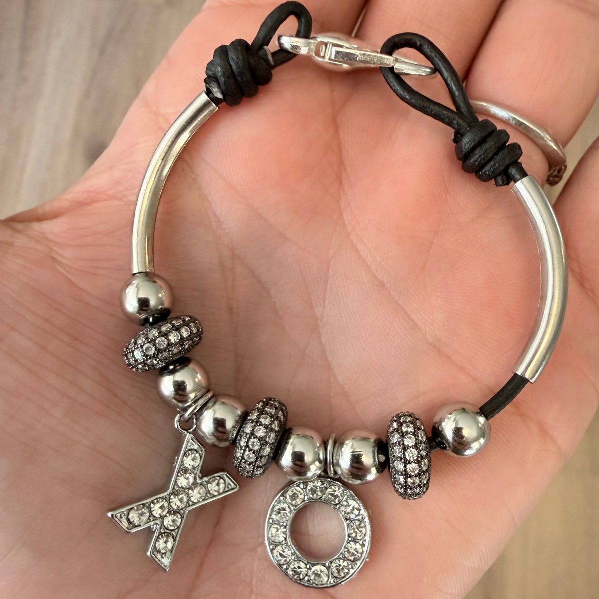 Women's black leather bracelet with silver XO charms, silver-tone beads, and pavé crystal accents.