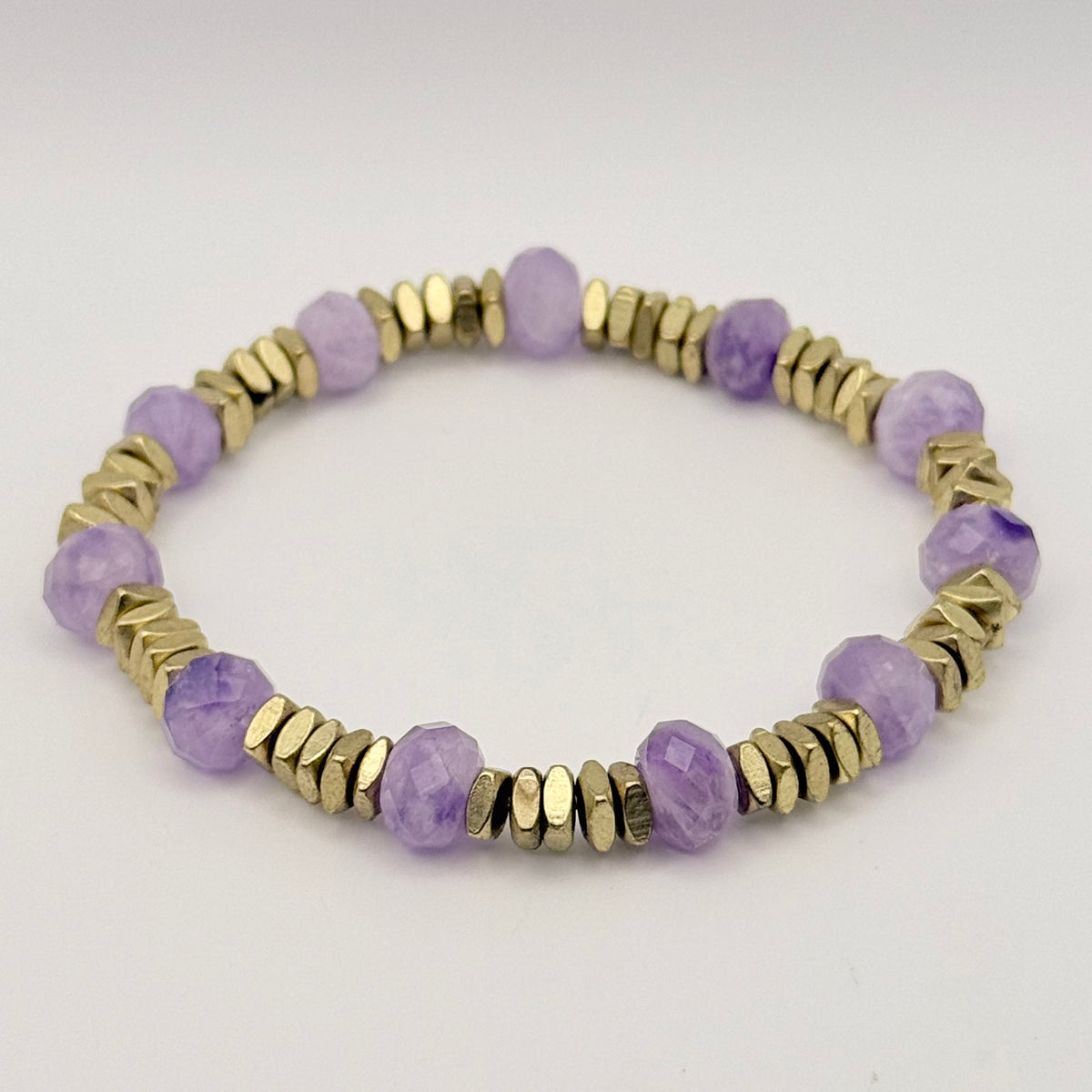 Bracelet with purple beads and gold accents on a white background
