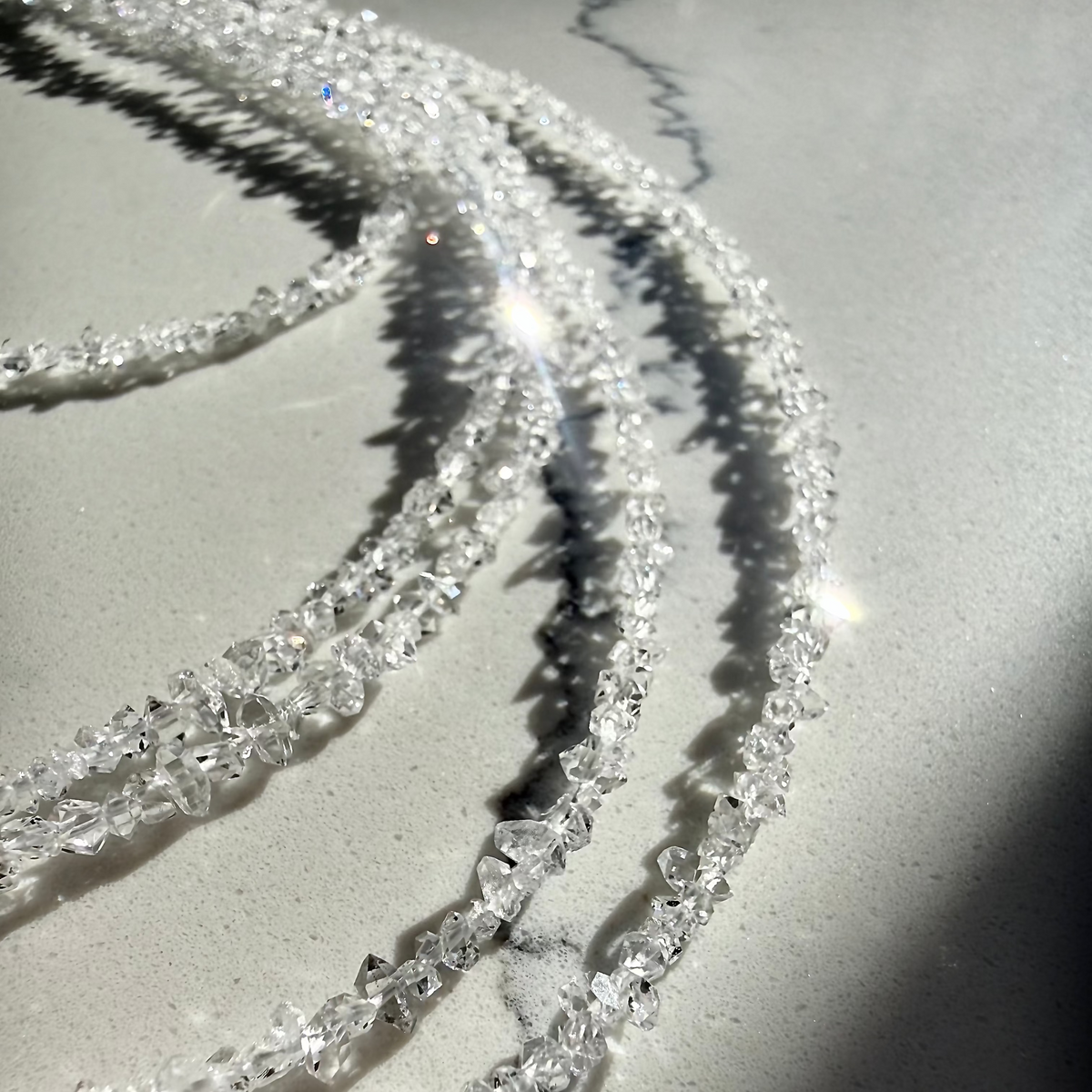 Close-up of a clear crystal necklace on a light background