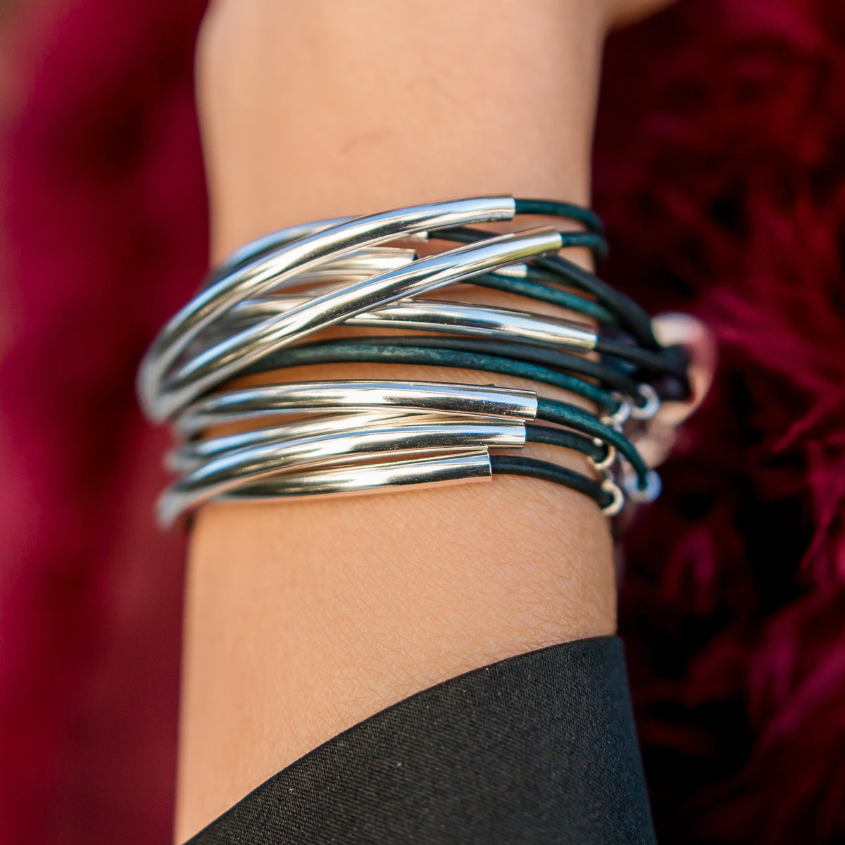 Close-up of Lizzy Classic Natural Peacock leather bracelet showing blue-green leather texture and silver-plated crescents.