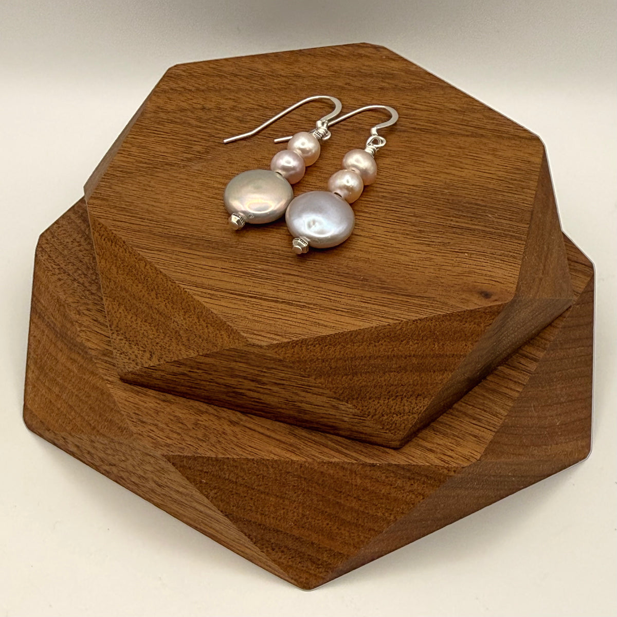 Pearl earrings on a wooden stand with a neutral background