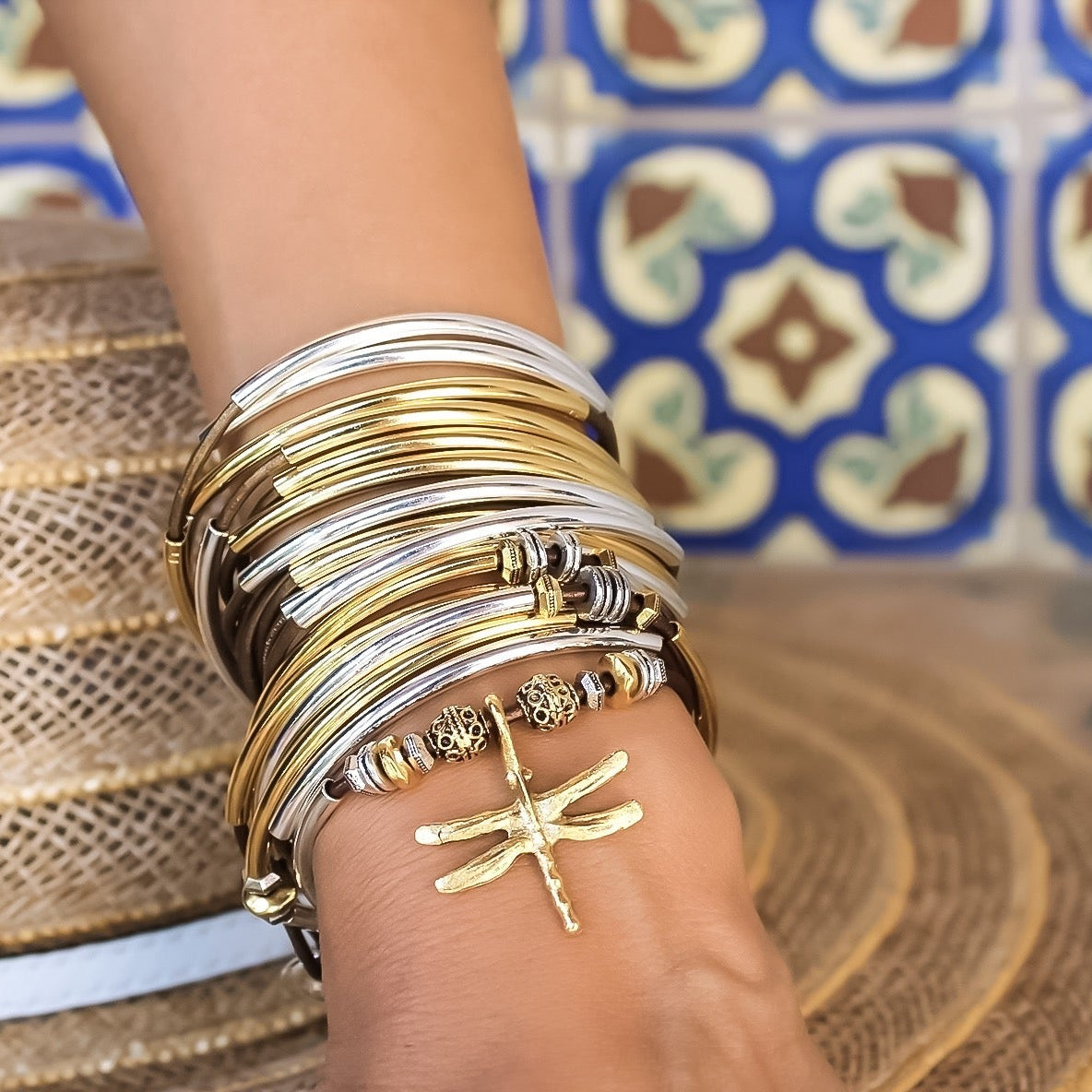 Person wearing multiple gold bracelets on a patterned background