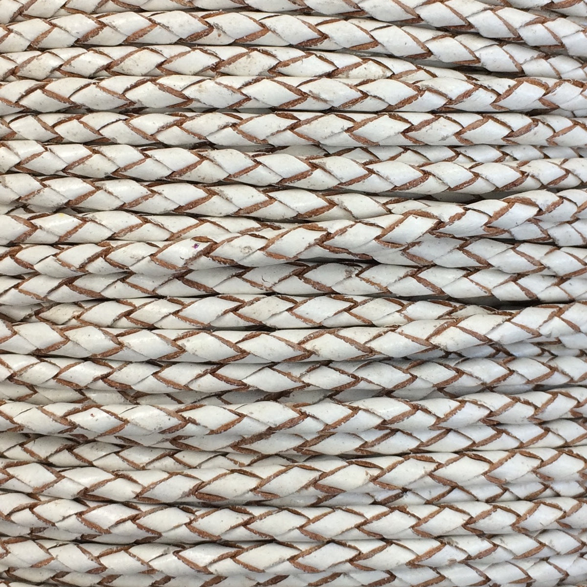 A close-up of braided rope or cord in an off-white color with thin brown twisted strands running through the center, filling the entire frame.