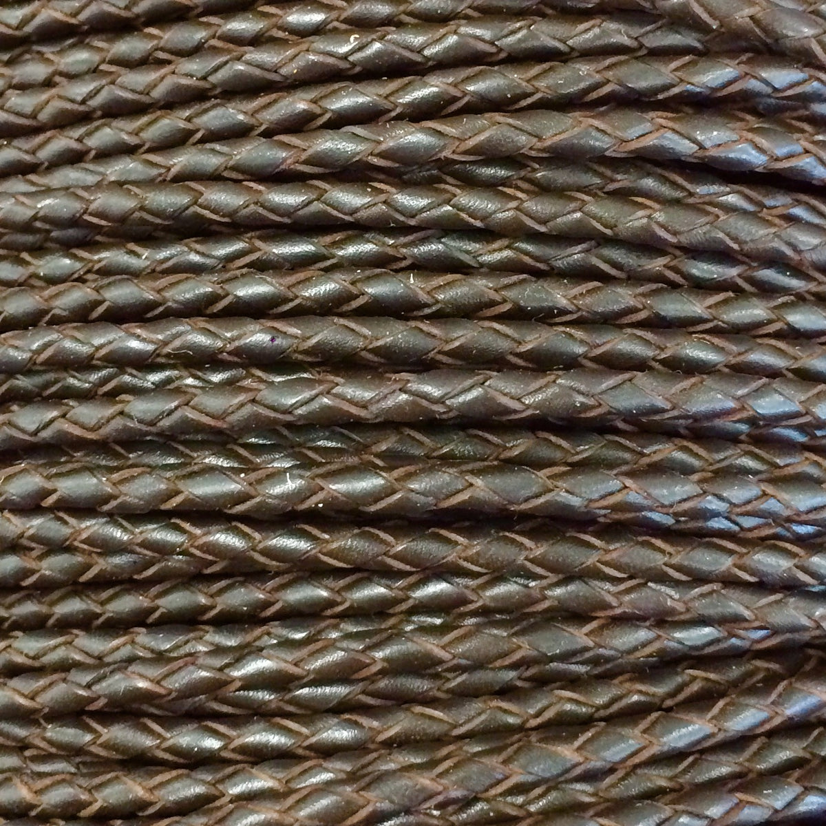 A close-up of a dark brown braided cord or strap with a textured, woven pattern.