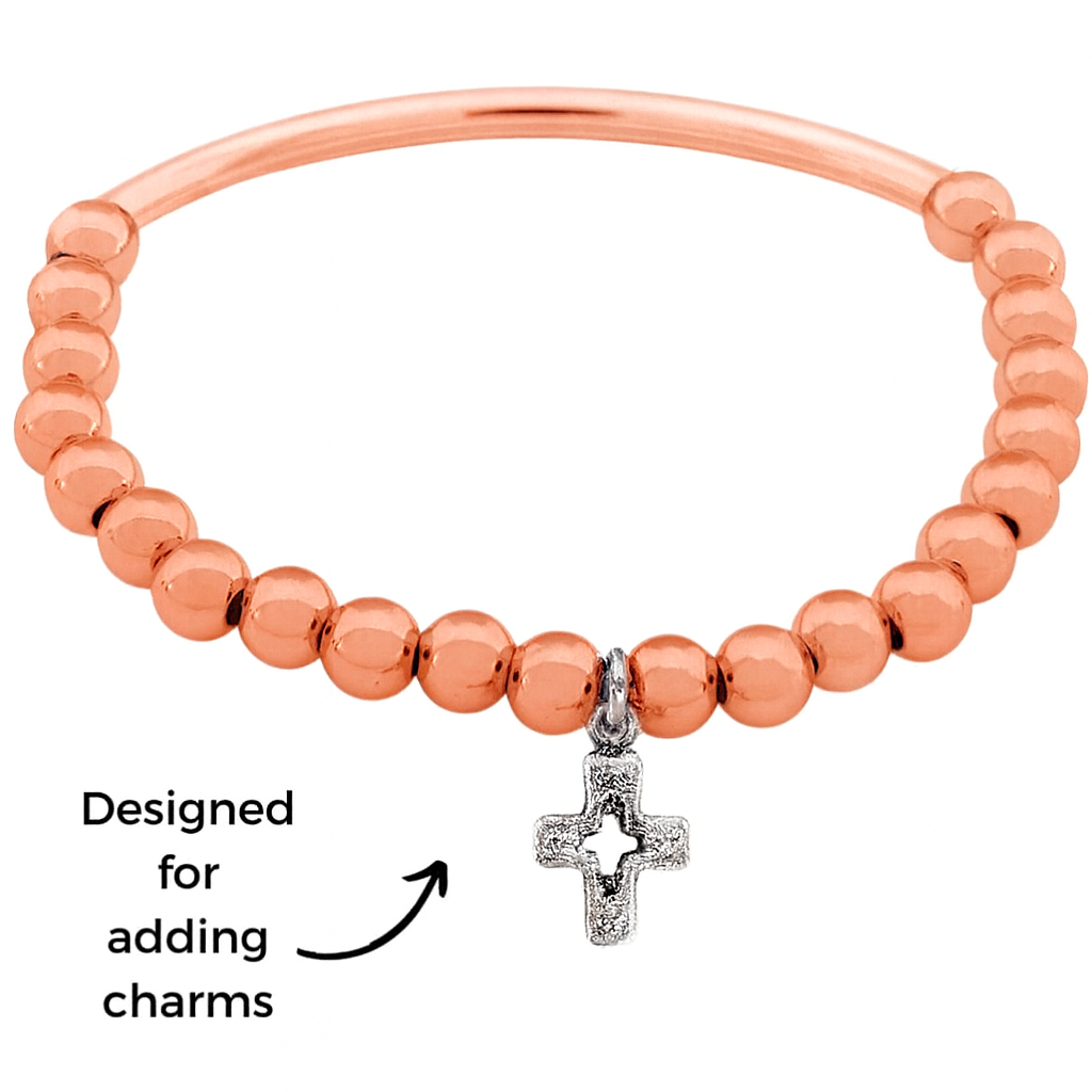 Rose gold beaded bracelet with a silver cross charm on a white background