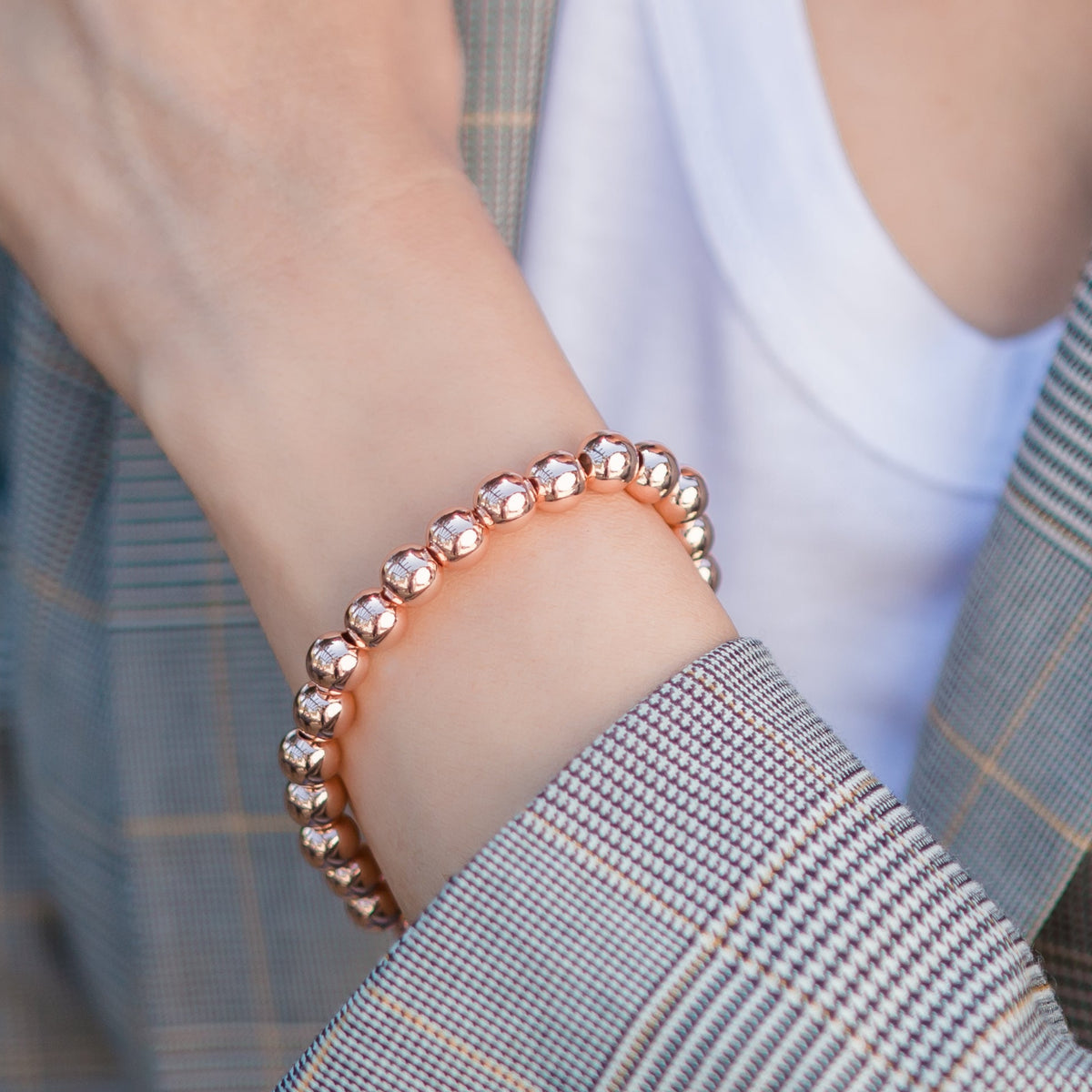 Person wearing a plaid blazer and bracelet with a blurred background