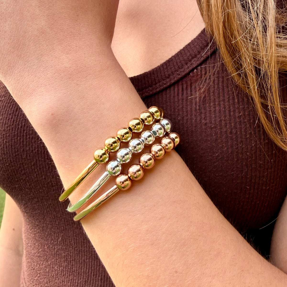 Three beaded bracelets on a wrist with a blurred background
