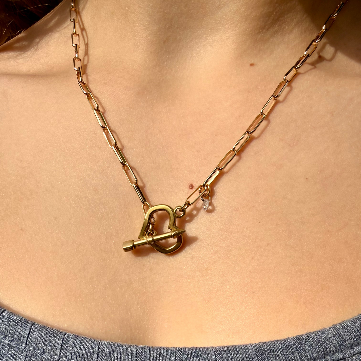 Gold necklace with a toggle clasp on a person wearing a blue top.