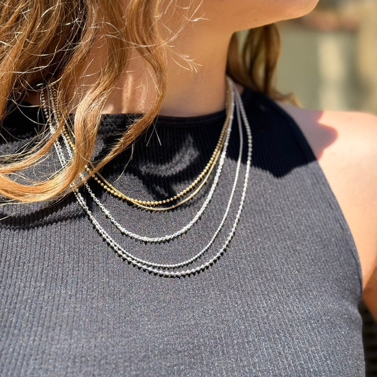 Close-up of a person wearing multiple necklaces with a blurred background