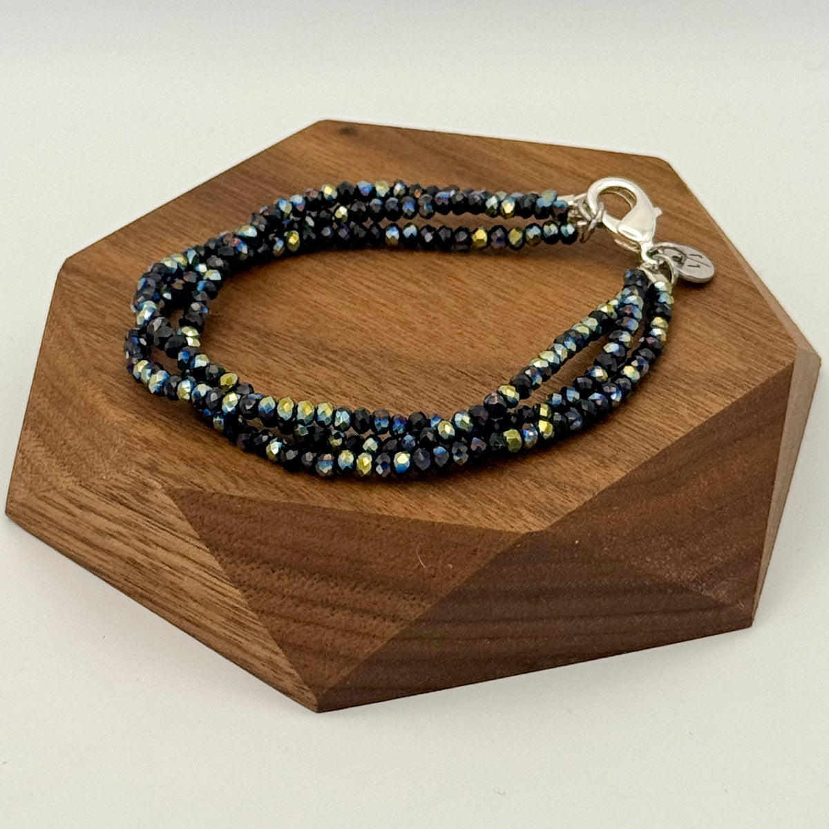 Multistrand beaded bracelet on a wooden stand with a white background
