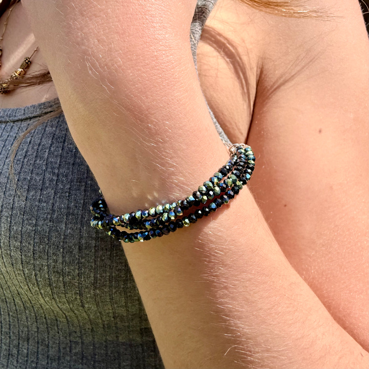 Close-up of a person's arm wearing a beaded bracelet with a blurred background