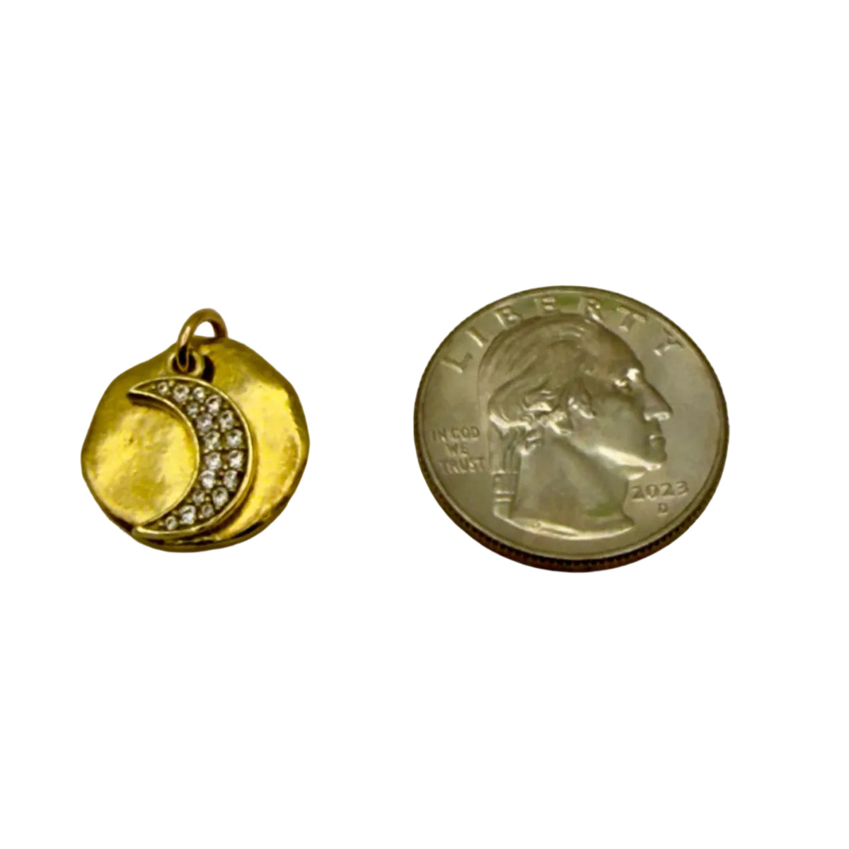 Gold pendant with a diamond crescent moon design next to a quarter on a gray background