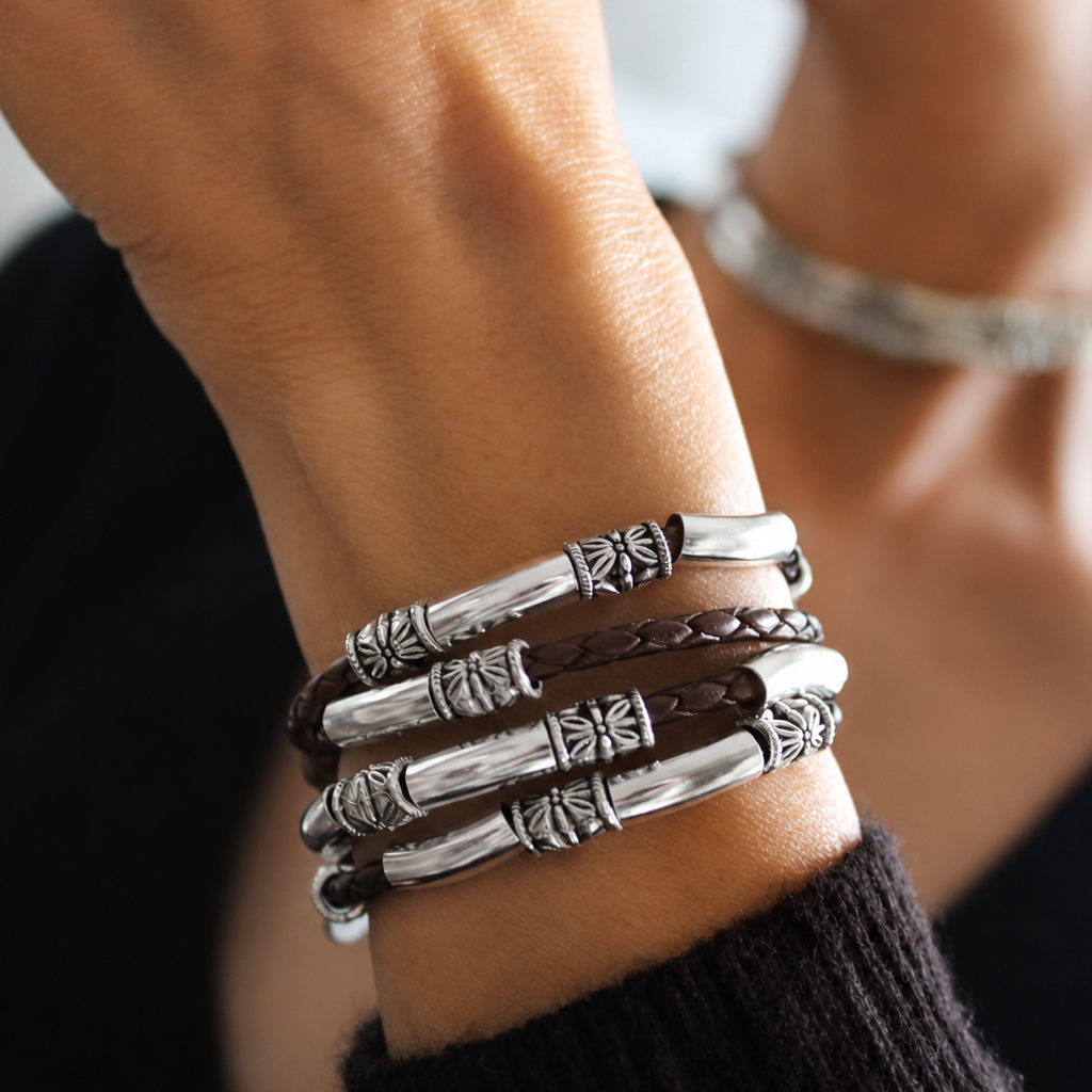 Close-up of a wrist wearing multiple silver bracelets with a blurred background