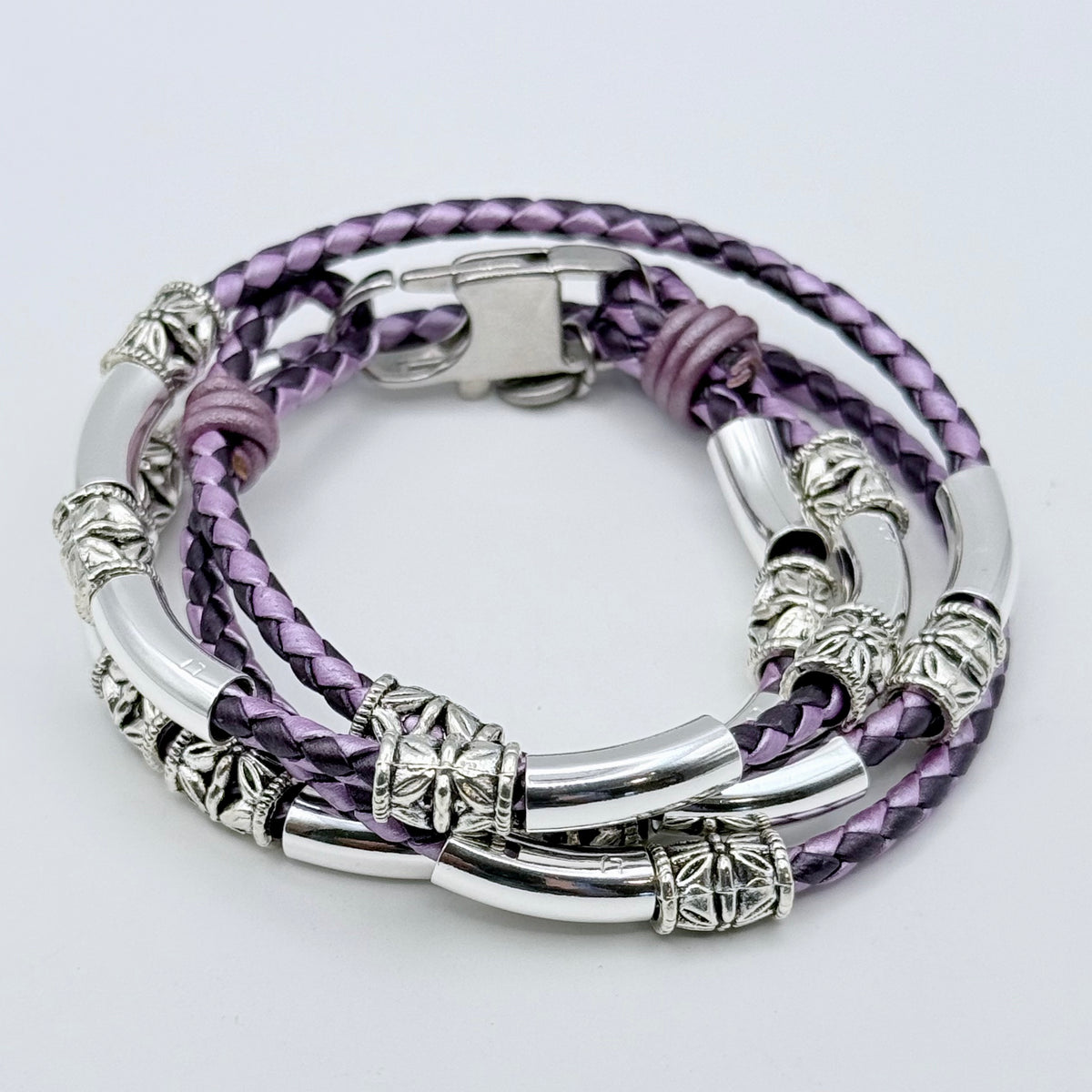 Purple braided leather bracelet with silver accents on a light gray background