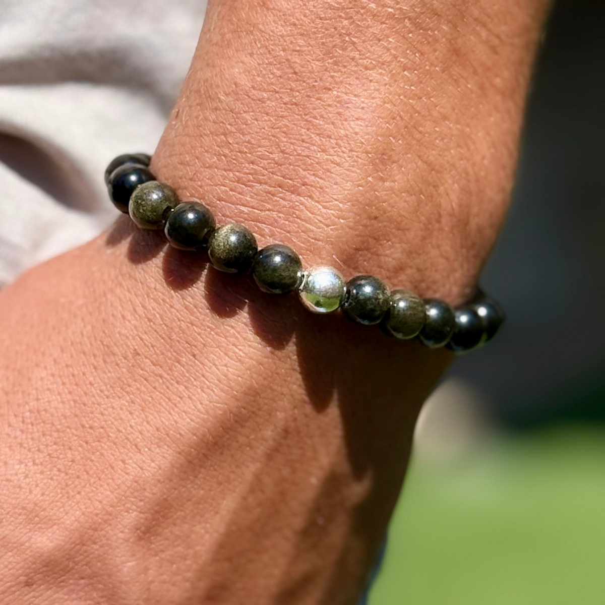 Close-up of a wrist wearing a black beaded bracelet with a blurred background