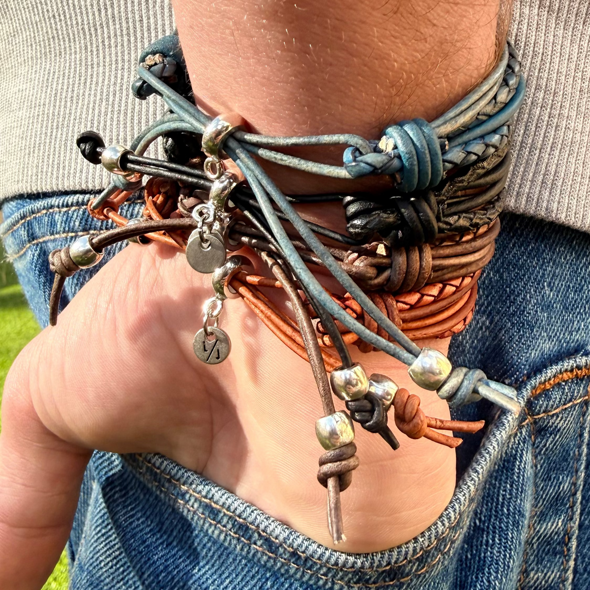 Close-up of a person's wrist wearing multiple leather bracelets with metal charms.