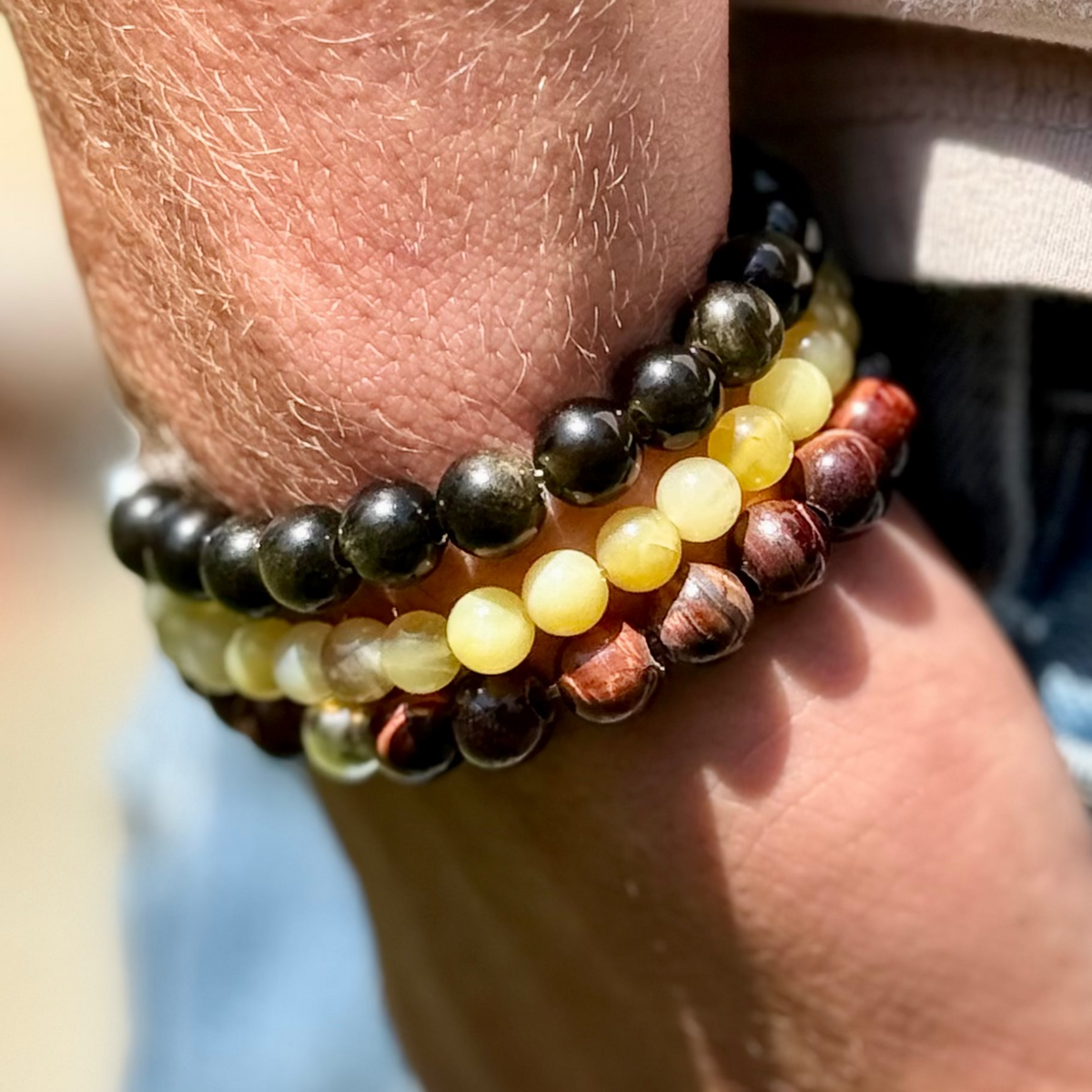 Close-up of a wrist wearing three beaded bracelets with a blurred background