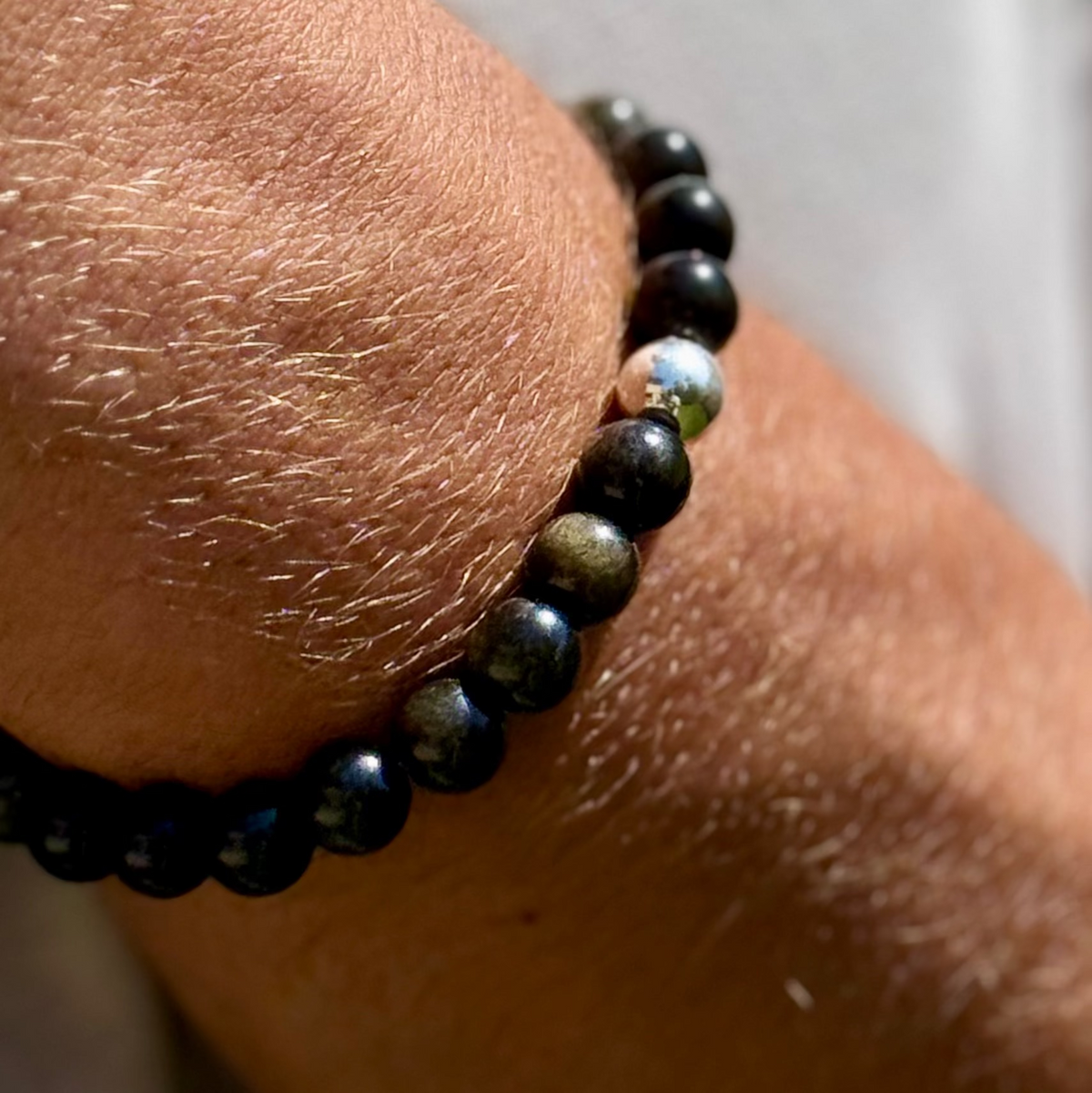 Close-up of a wrist wearing a black beaded bracelet with a silver clasp.