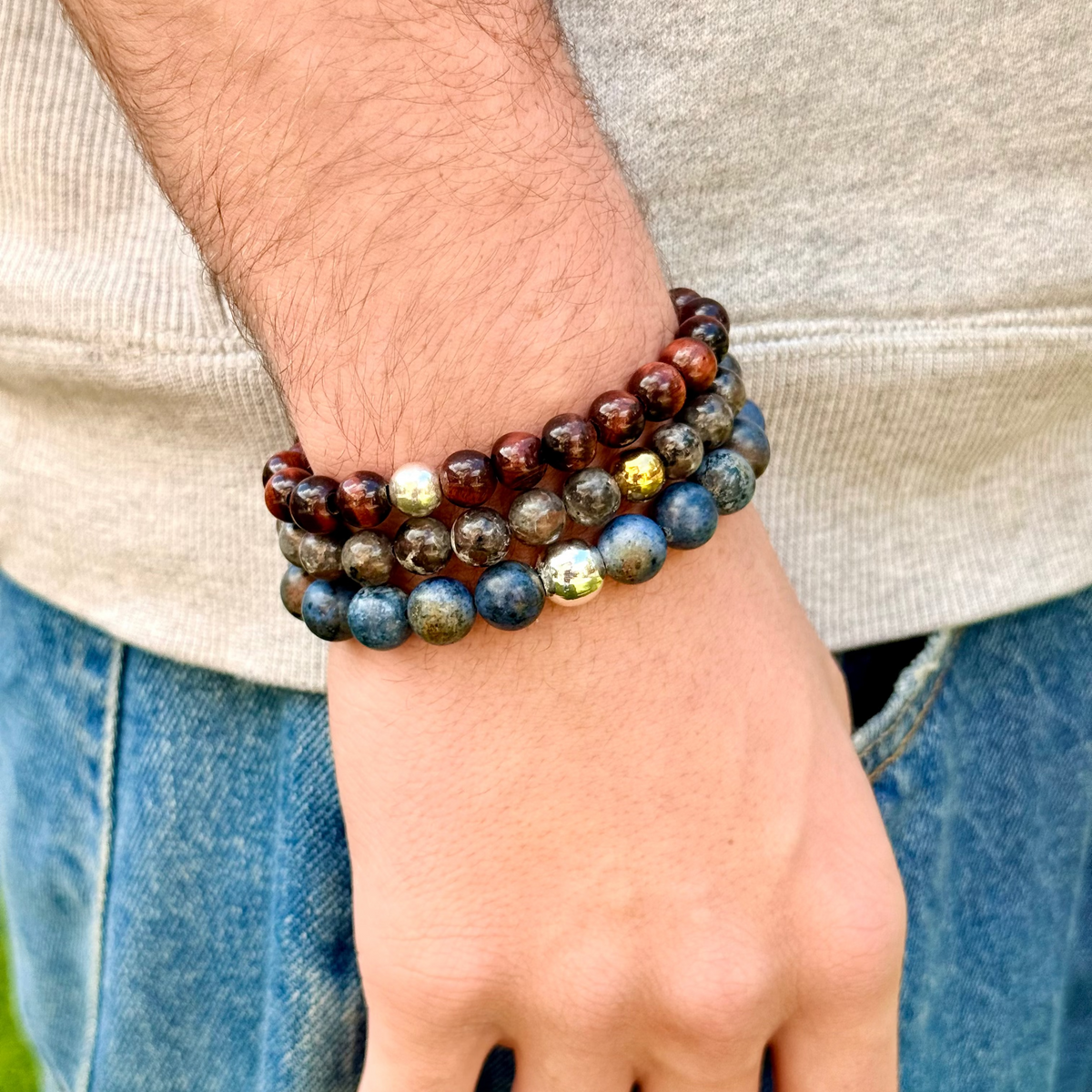 Close-up of a person's wrist wearing two beaded bracelets with a neutral background