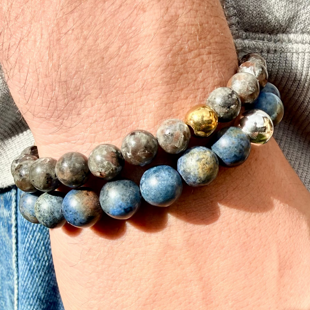Close-up of a wrist wearing a stack of blue beaded bracelets with gold accents.