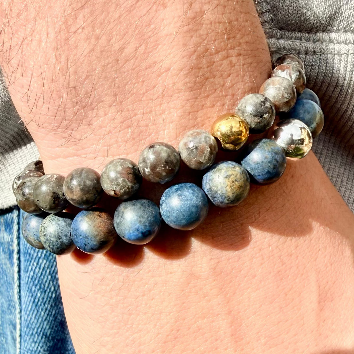 Close-up of a wrist wearing a stack of blue beaded bracelets with gold accents.