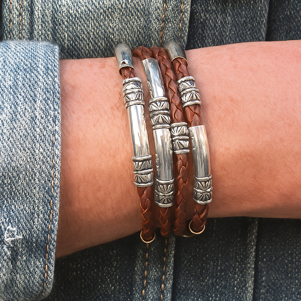 Bracelets with brown leather and silver metal on a wrist against a denim background