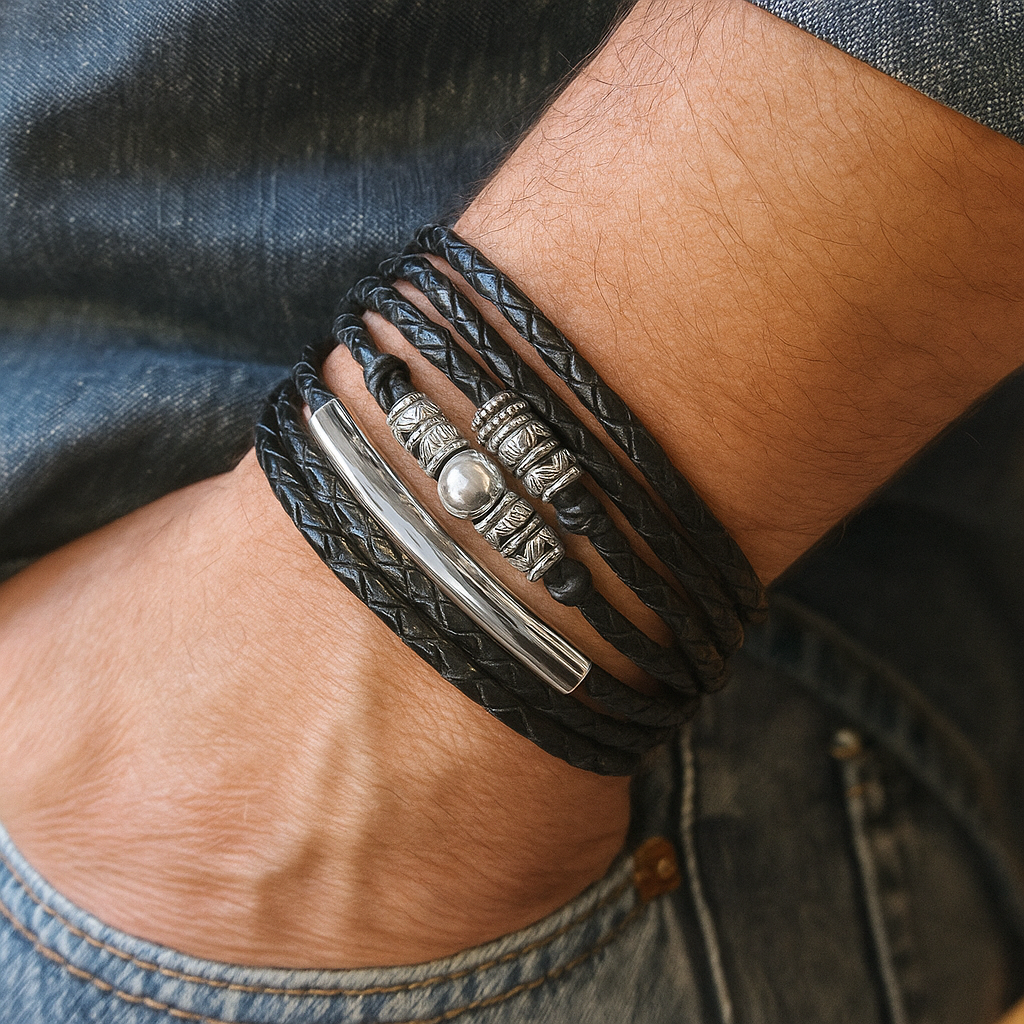 Close-up of a person's wrist wearing a black braided leather bracelet with silver metal elements.