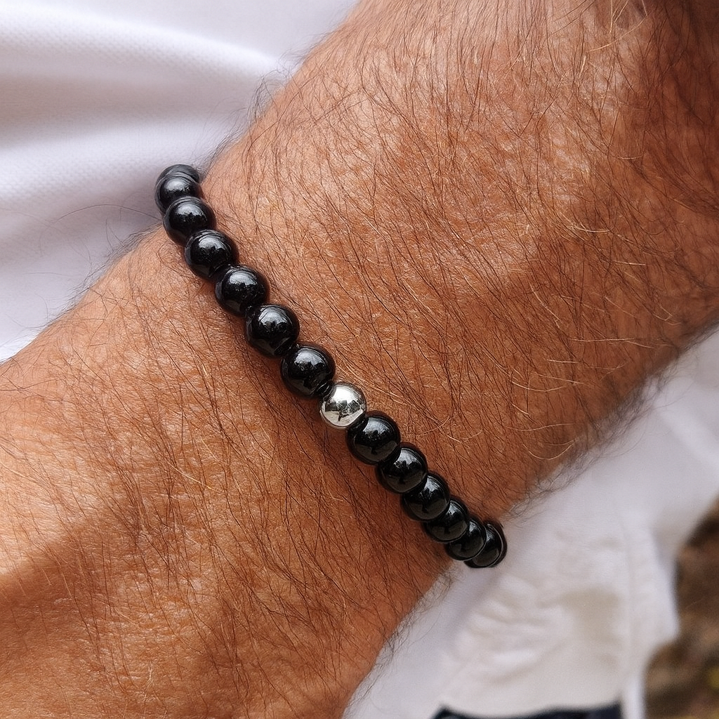 Black beaded bracelet on a wrist with a blurred background
